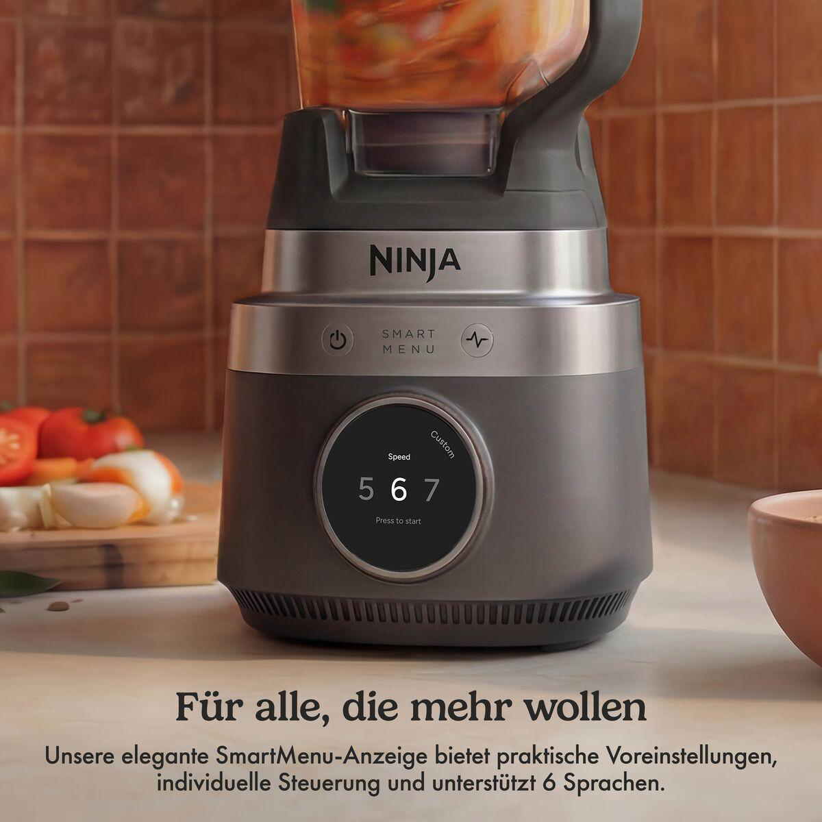 Ein Ninja-Mixer mit digitalem Display auf einer Küchenzeile neben Gemüse.