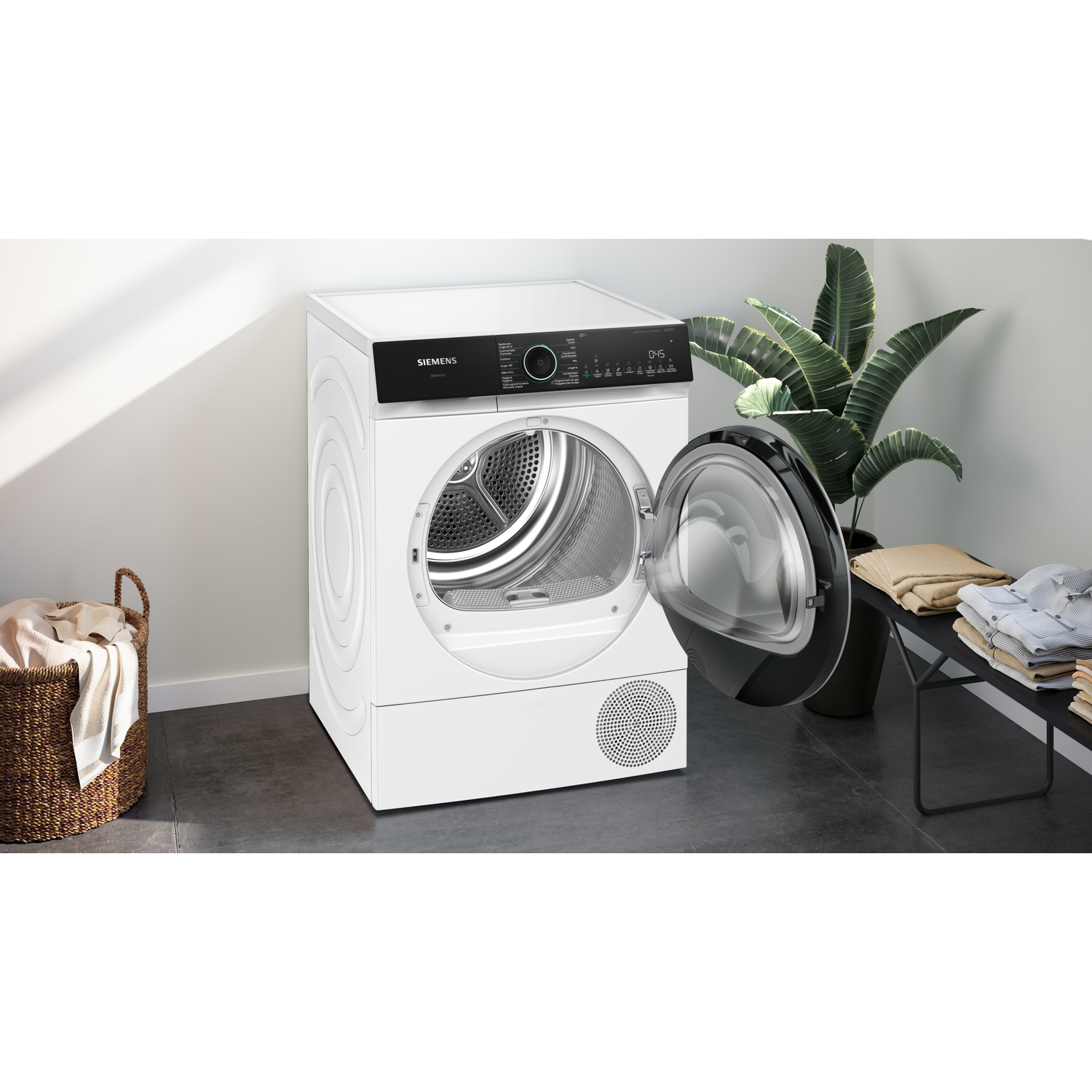 Witte Siemens wasdroger met open deur in een moderne kamer met een plant en opgevouwen kleding.