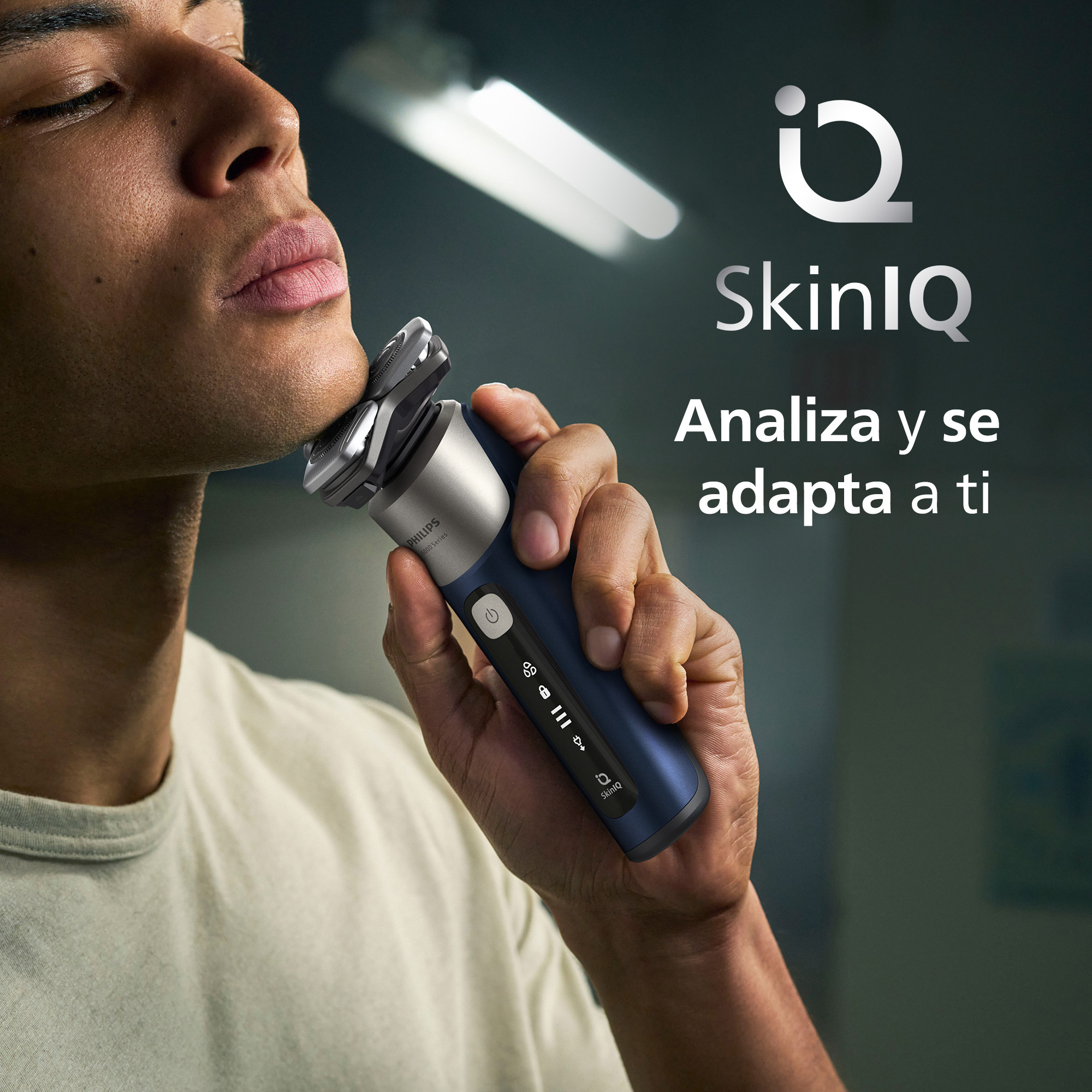 Un hombre se afeita con una afeitadora Philips SkinIQ azul y plateada.