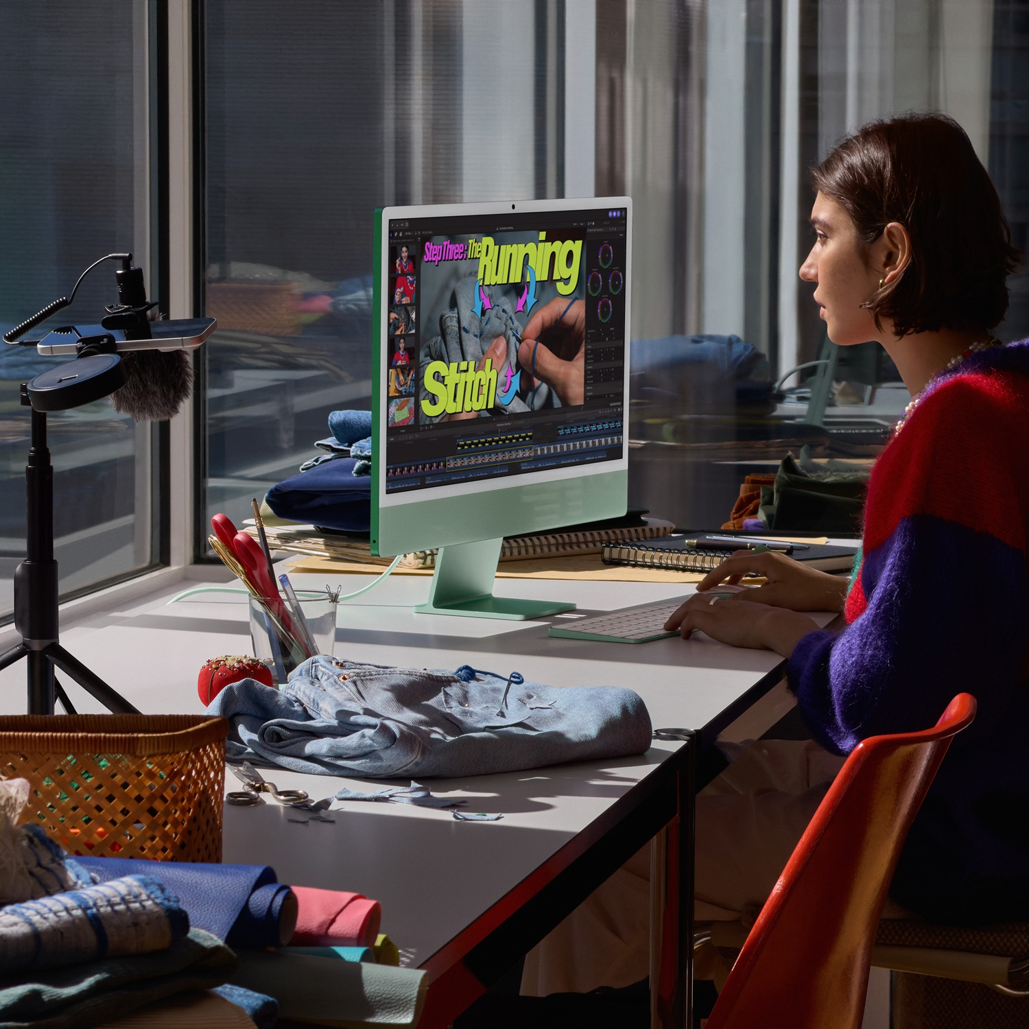 Een vrouw werkt op een groene computer in een lichte kamer met knutselspullen.