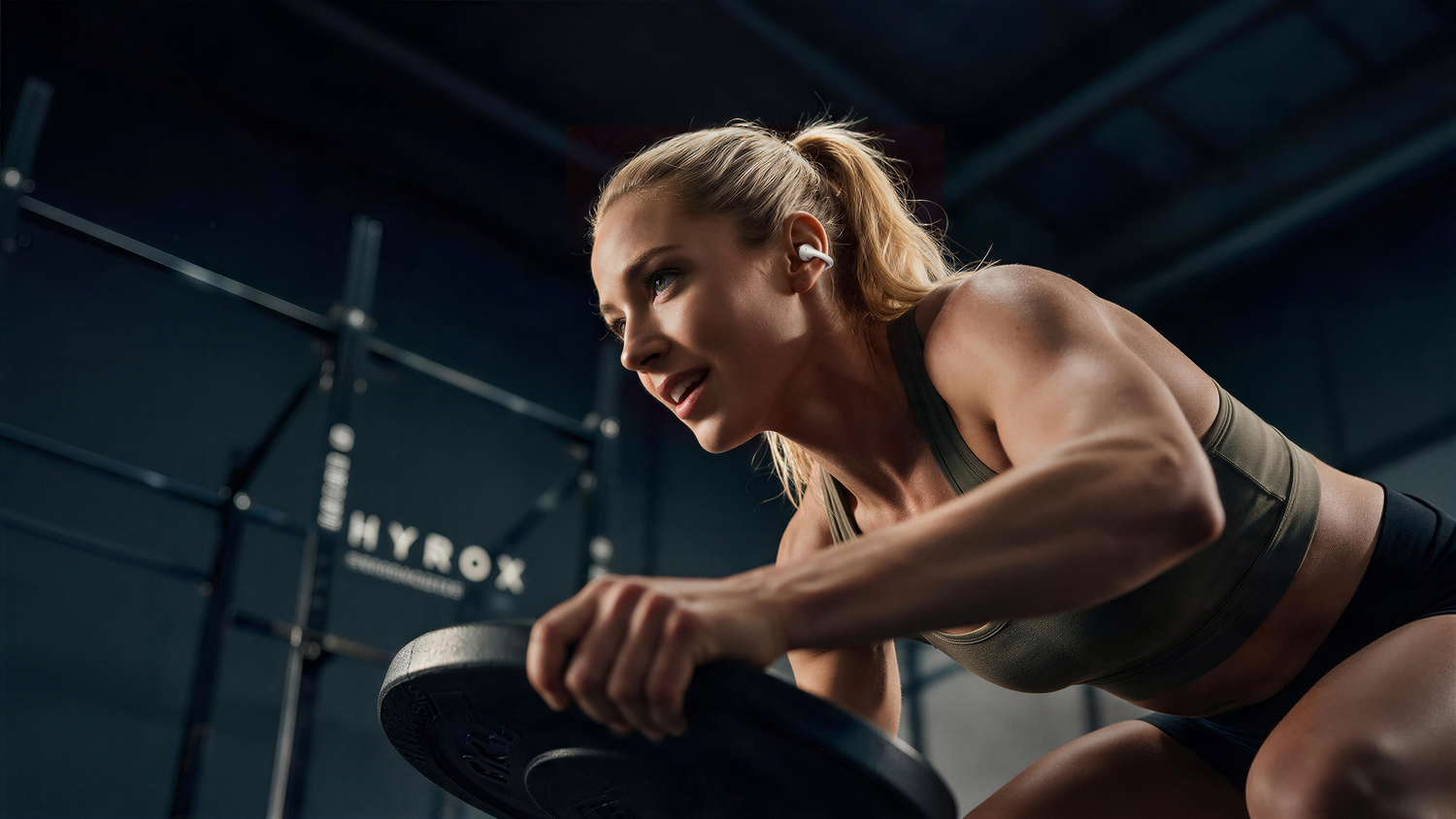 Una atleta rubia con ropa deportiva entrena en un gimnasio oscuro sosteniendo un disco de pesas.