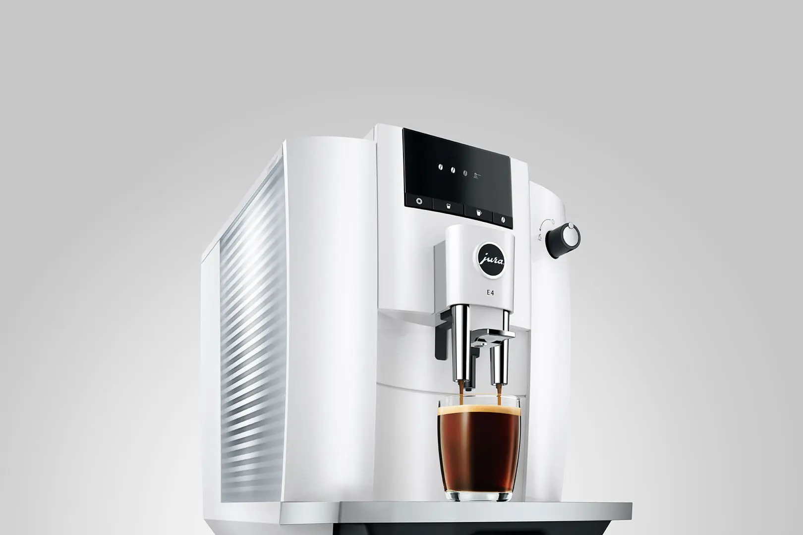 Una cafetera blanca Jura E4 prepara espresso en una taza de vidrio sobre fondo gris.