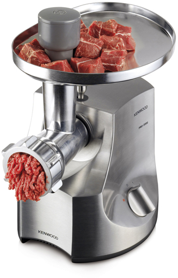 Ein Fleischwolf aus Edelstahl mit rohen Fleischwürfeln im Trichter und auslaufendem Hackfleisch.
