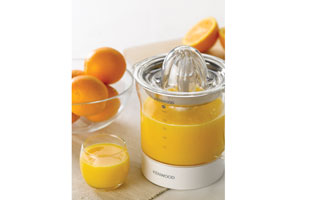 Orangensaftzubereitung. Saftpresse, Orangen und ein Glas Saft im Bild.
