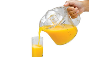 Ein Glas Kenwood Entsafter gießt Orangensaft in ein hohes Glas. Hand sichtbar.