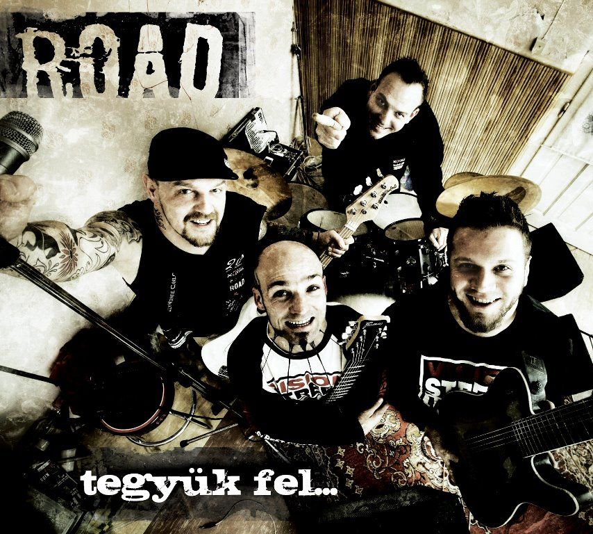 Négy férfiból álló zenekar fotója. Mosolyognak és hangszereket tartanak, 'ROAD' logóval.