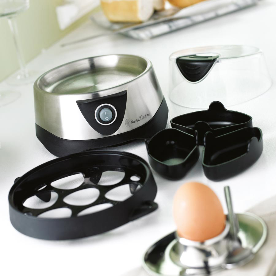 An egg boiler with several accessories on a white surface.