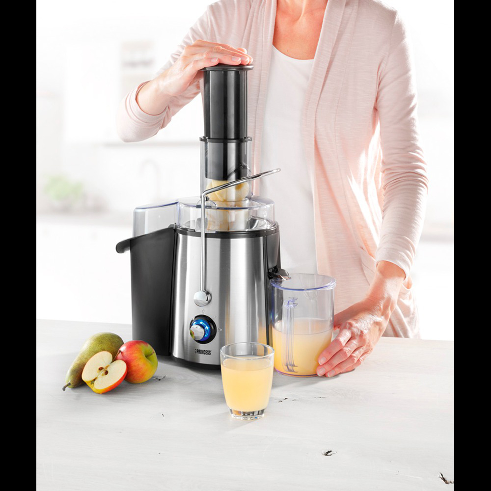 Een vrouw perst fruit. Een juicer met appels en peren op een witte tafel.