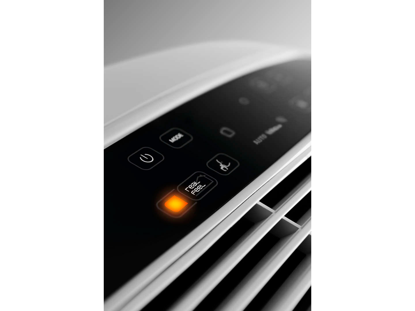 Close up of a white control panel with an orange lit button.