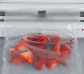 Image of sliced strawberries in a plastic bag, sealed. White background, close-up.