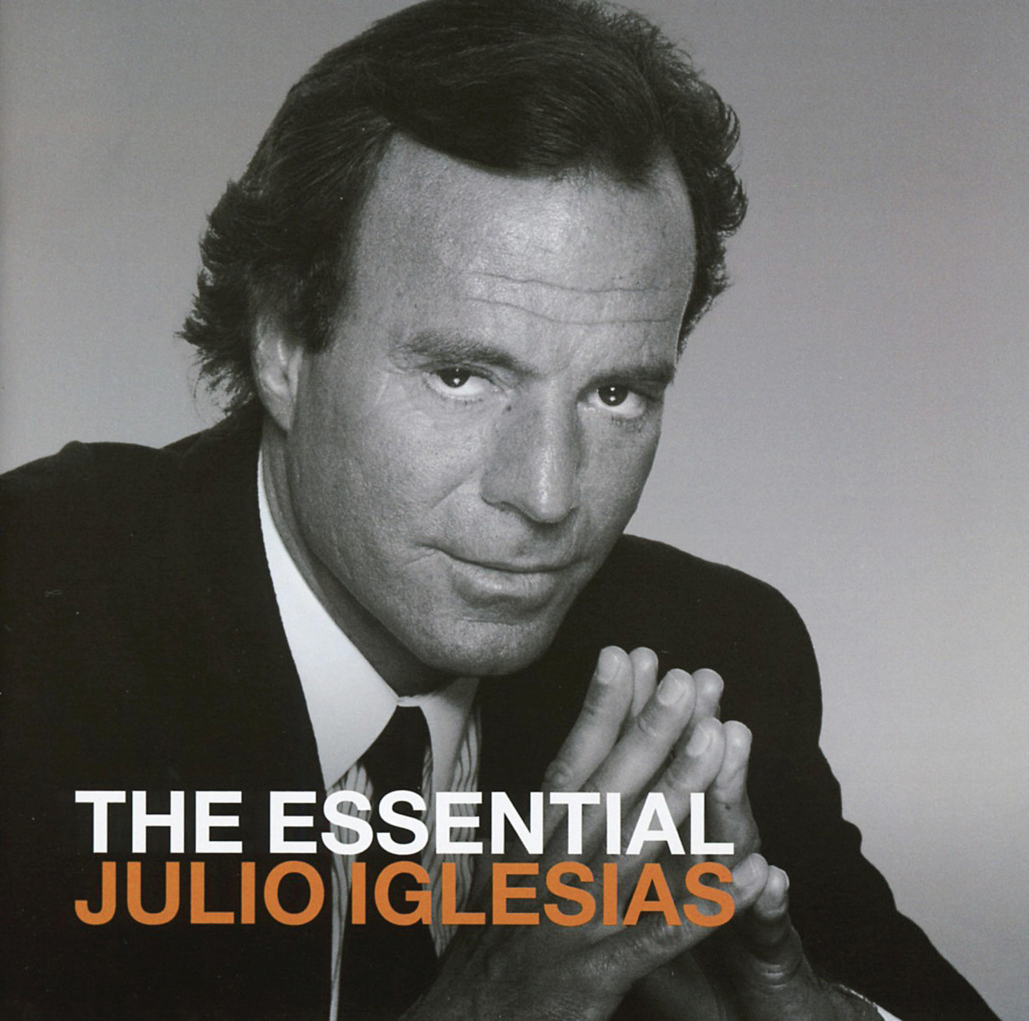 Albumcover. Julio Iglesias im Anzug, Blick zum Betrachter, Hände gefaltet. Titel: The Essential Julio Iglesias.