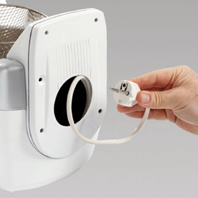 A hand plugging a white power cord into a white appliance.