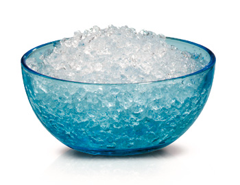 Een blauwe glazen kom gevuld met crushed ice. Het ijs is helder en de kom staat op een wit oppervlak.