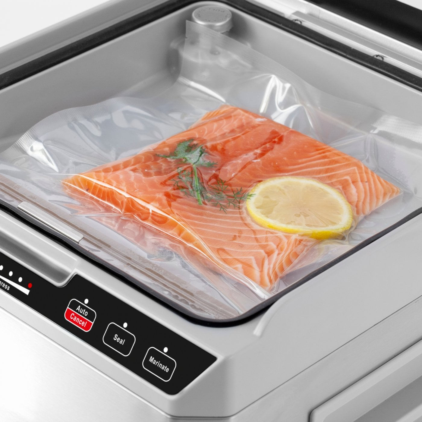 Ein Lachsfilet in einem vakuumversiegelten Beutel in einem Vakuumierer. Eine Zitronenscheibe ist enthalten.