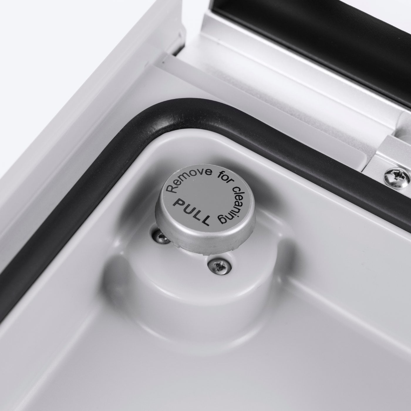 Nahaufnahme eines grauen Knopfes mit der Aufschrift 'Remove for cleaning, pull'.