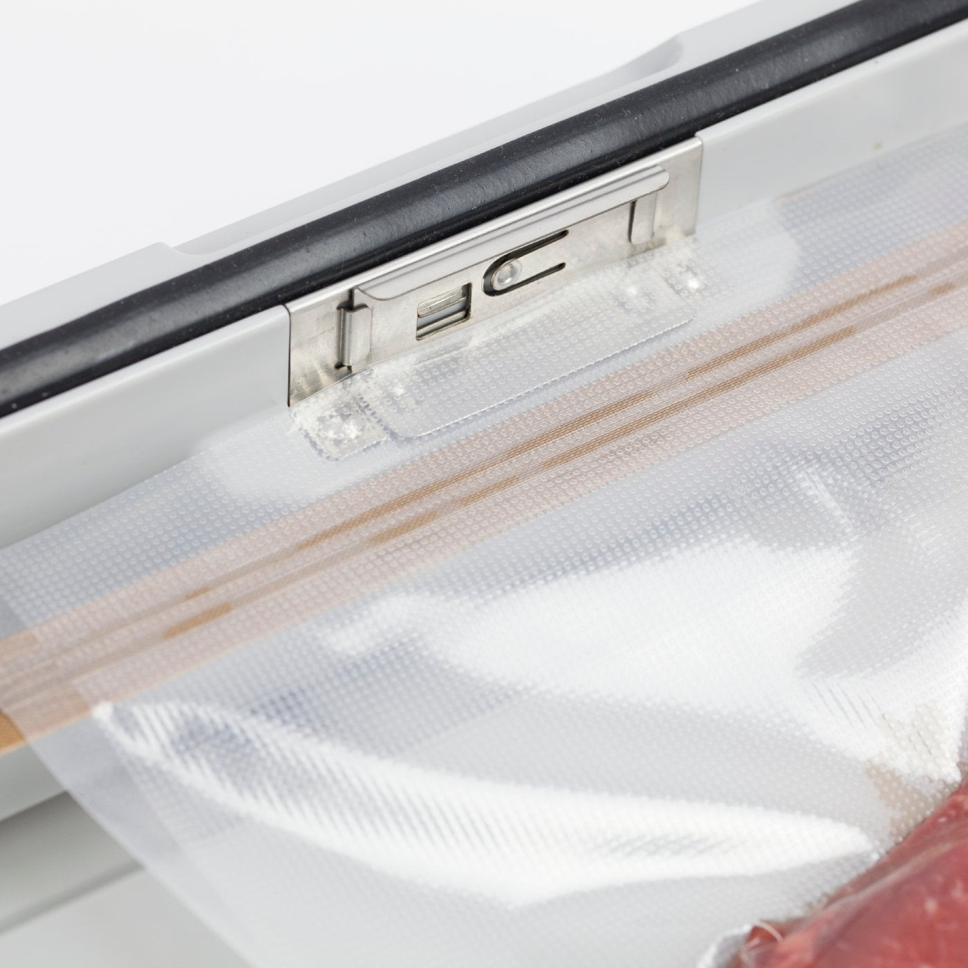 Nahaufnahme eines Vakuumversiegelungsgeräts mit einer durchsichtigen Plastiktüte darin. Die Tüte ist teilweise versiegelt.