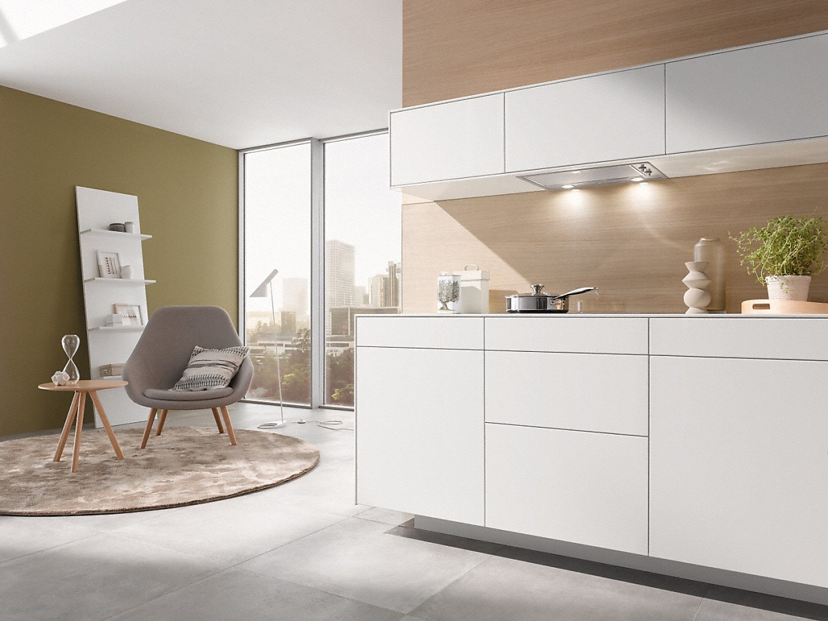 Moderne weiße Küche mit weißen Schränken, hellem Holz und olivfarbener Wand.
