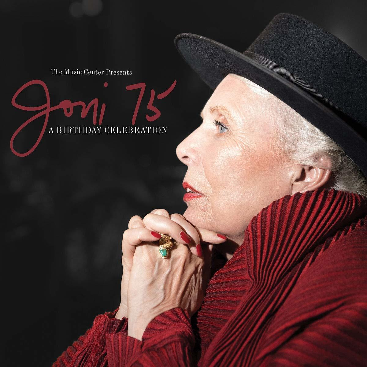 Joni Mitchell, profil, portant un chapeau noir et un manteau rouge, mains jointes, fond sombre.