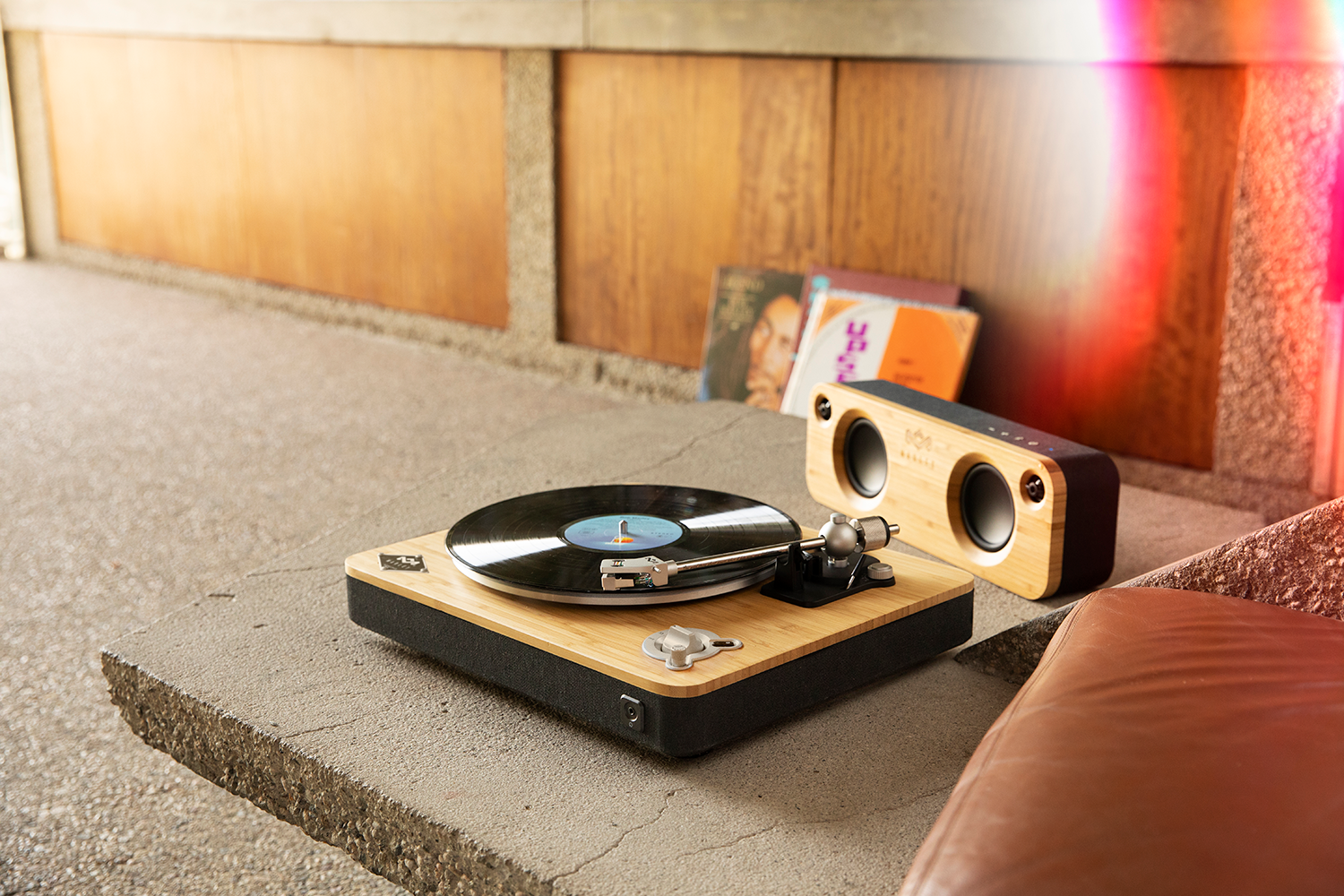 Een platenspeler met een vinylplaat die afspeelt, een luidspreker en platen op de achtergrond.