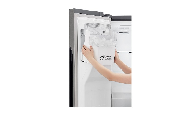 Una persona quitando una cubitera de un refrigerador. La bandeja está llena de cubitos de hielo.