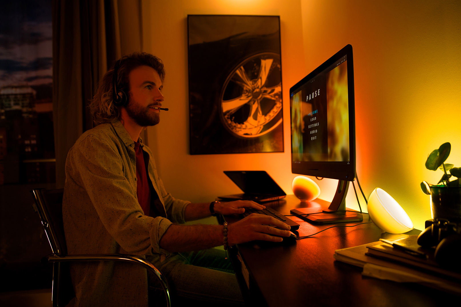 Mann spielt am Schreibtisch mit Monitor, Tastatur und Schreibtischlampe.