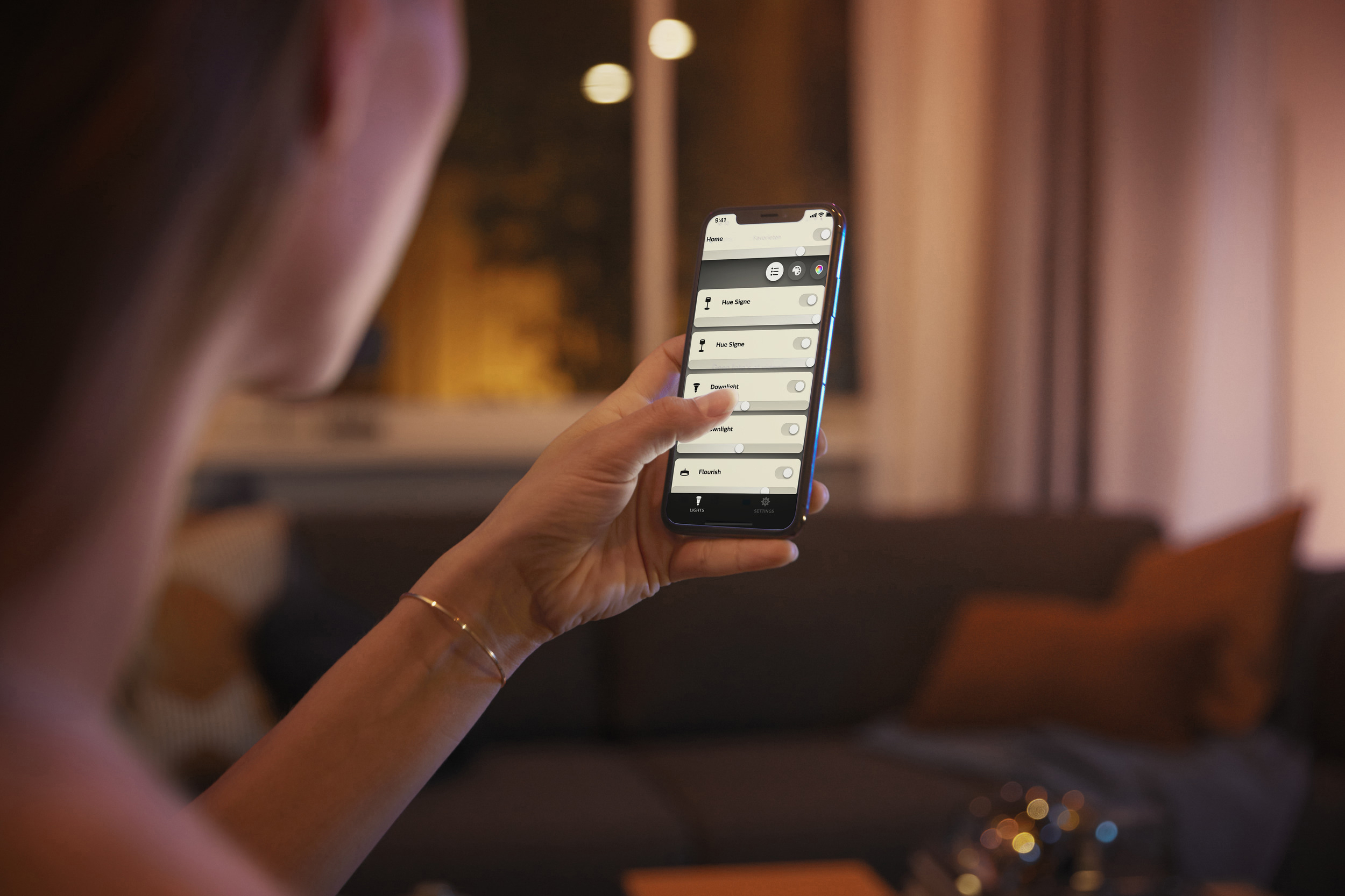 Person hält ein Smartphone mit einer Smart-Home-App-Oberfläche.