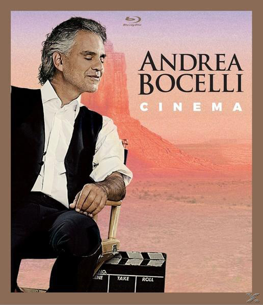Andrea Bocelli sitzt mit geschlossenen Augen auf einem Stuhl, vor ihm eine Filmklappe; KINO.