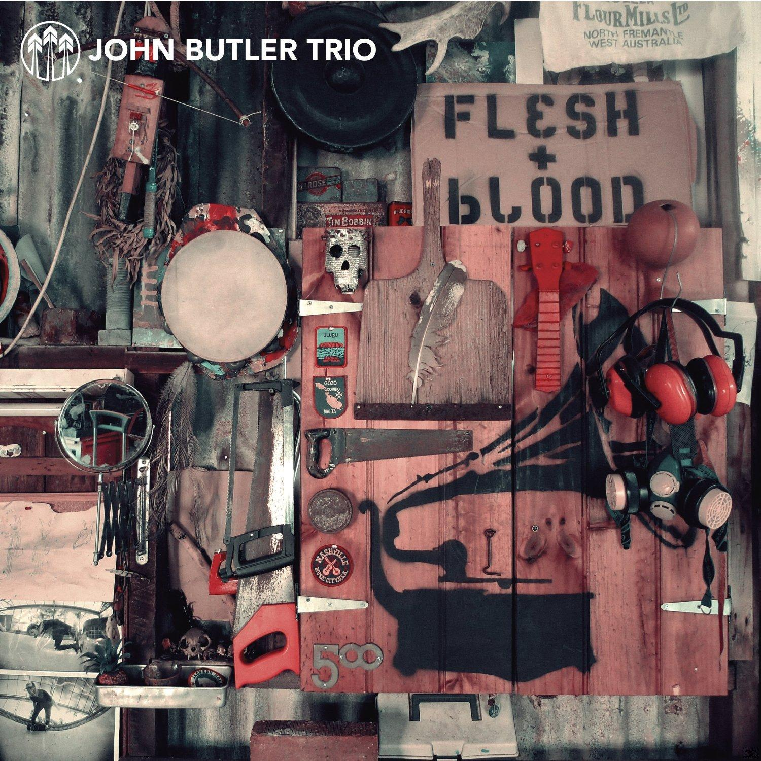 Albumcover von John Butler Trio, mit Holzplankenwand mit Werkzeugen und Musikinstrumenten.