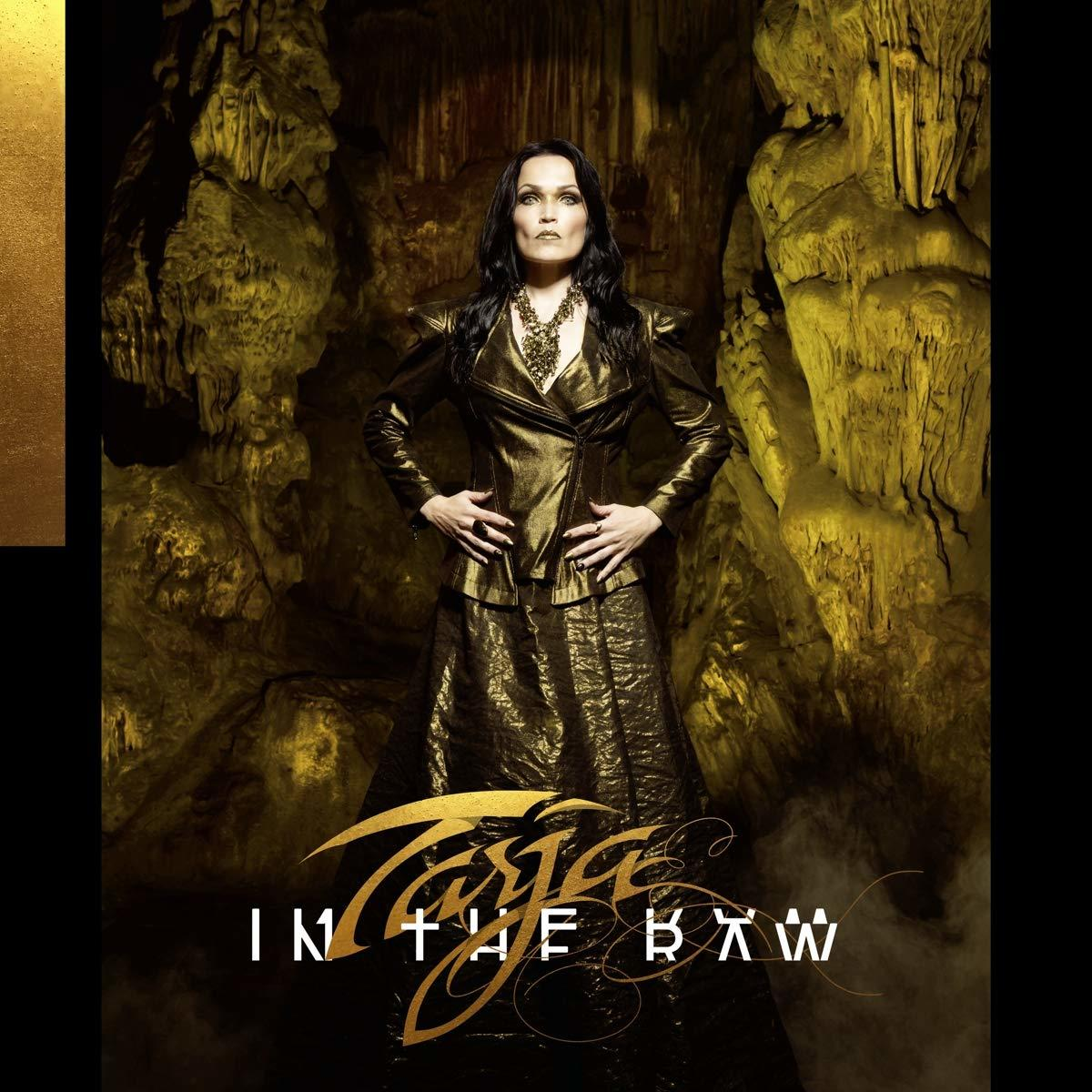 Frau in goldenem Outfit steht in einer Höhle. Der Albumtitel "IN THE RAW" ist unten zu sehen.