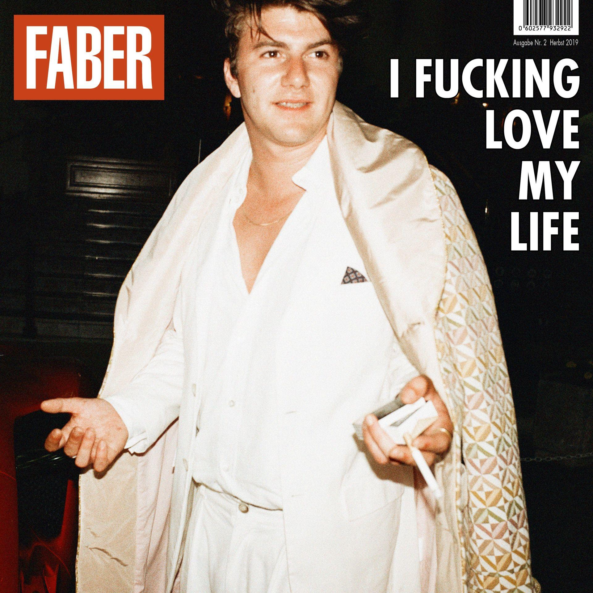 Mann in weißem Hemd, der eine Zigarettenschachtel hält. Der Titel lautet: „I Fucking Love My Life“.