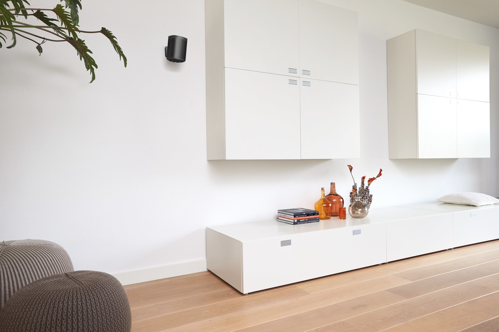 Ein minimalistisches Wohnzimmer mit weißen Wänden, einem weißen Schrank und Holzboden, mit Dekoration.