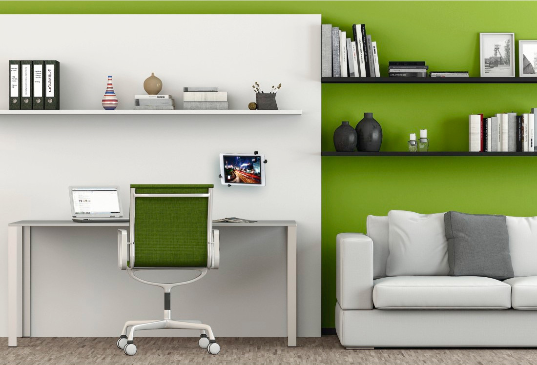 Environnement de bureau avec bureau blanc, chaise verte et étagères avec objets et un canapé blanc.