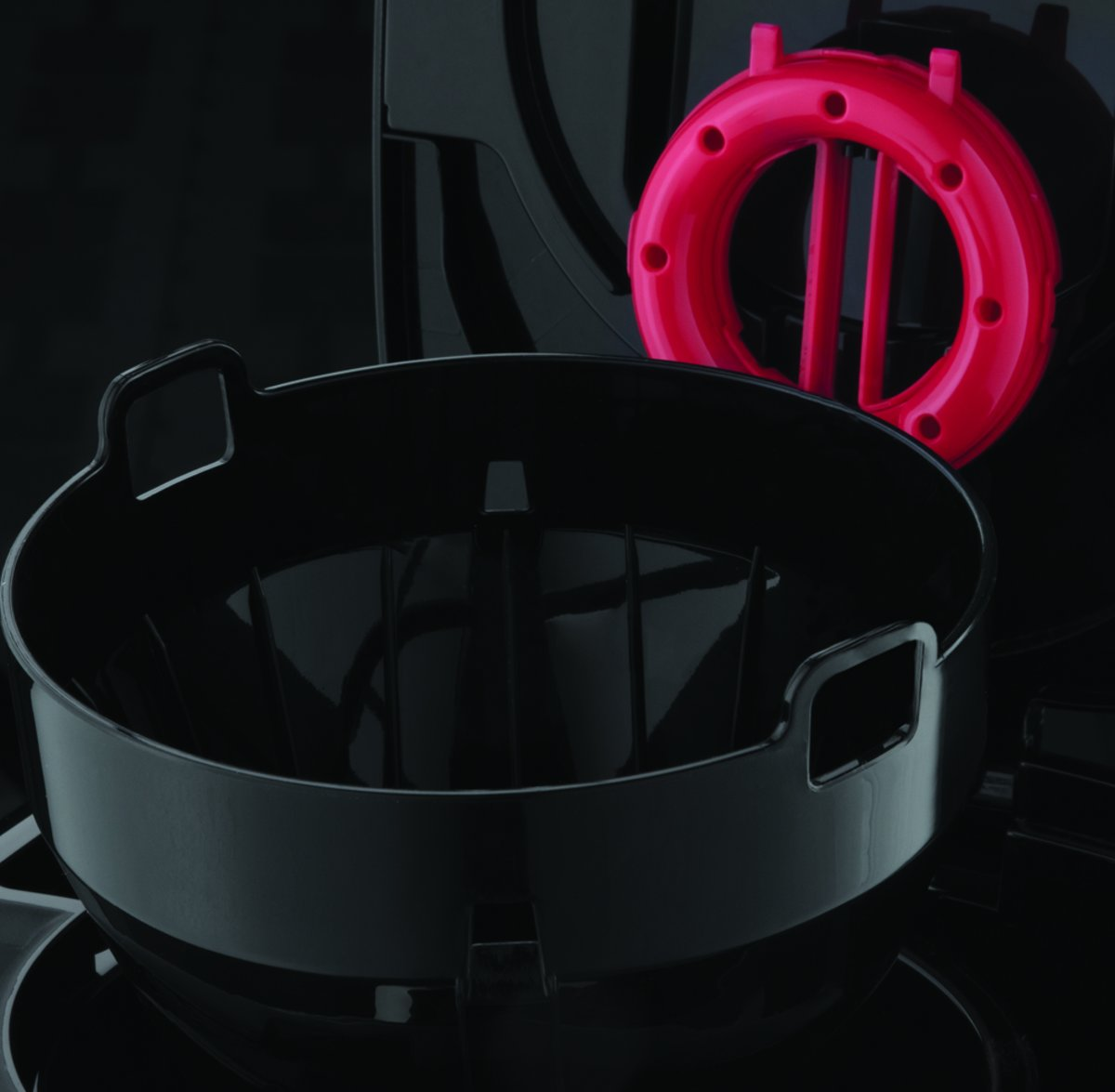 Black and pink kitchen appliance components. A black bowl and a pink ring.