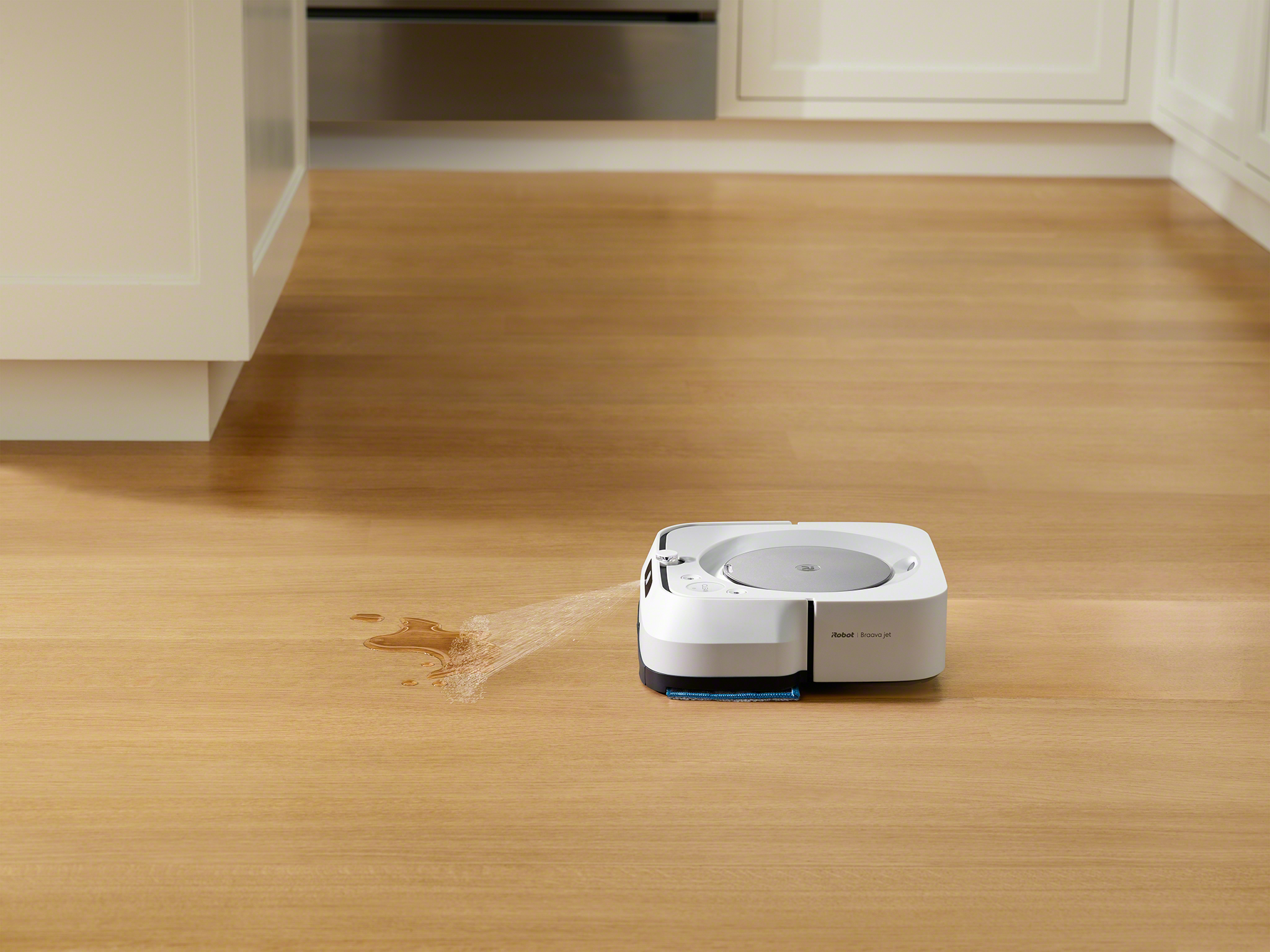 Robot vacuum cleaner cleaning a wood floor with a water spray.