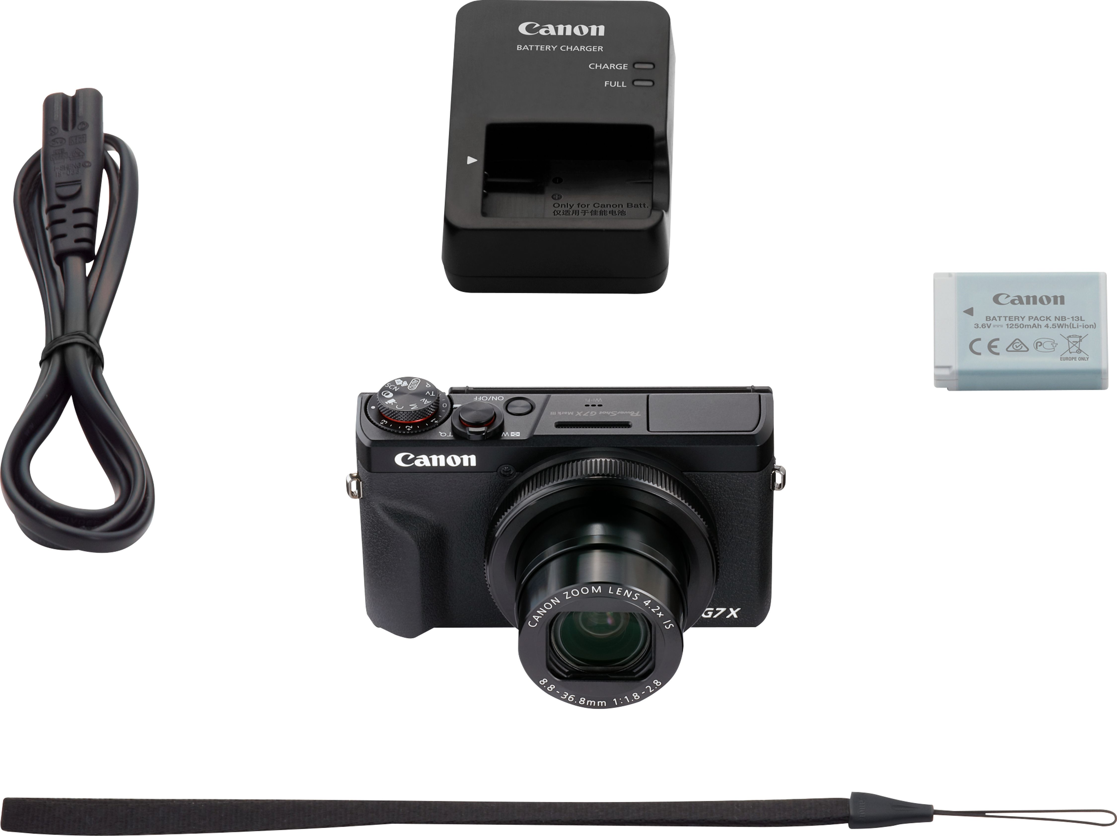 Fotocamera Canon G7X, caricabatterie, batteria e cinturino. La fotocamera è nera con un obiettivo sul davanti.