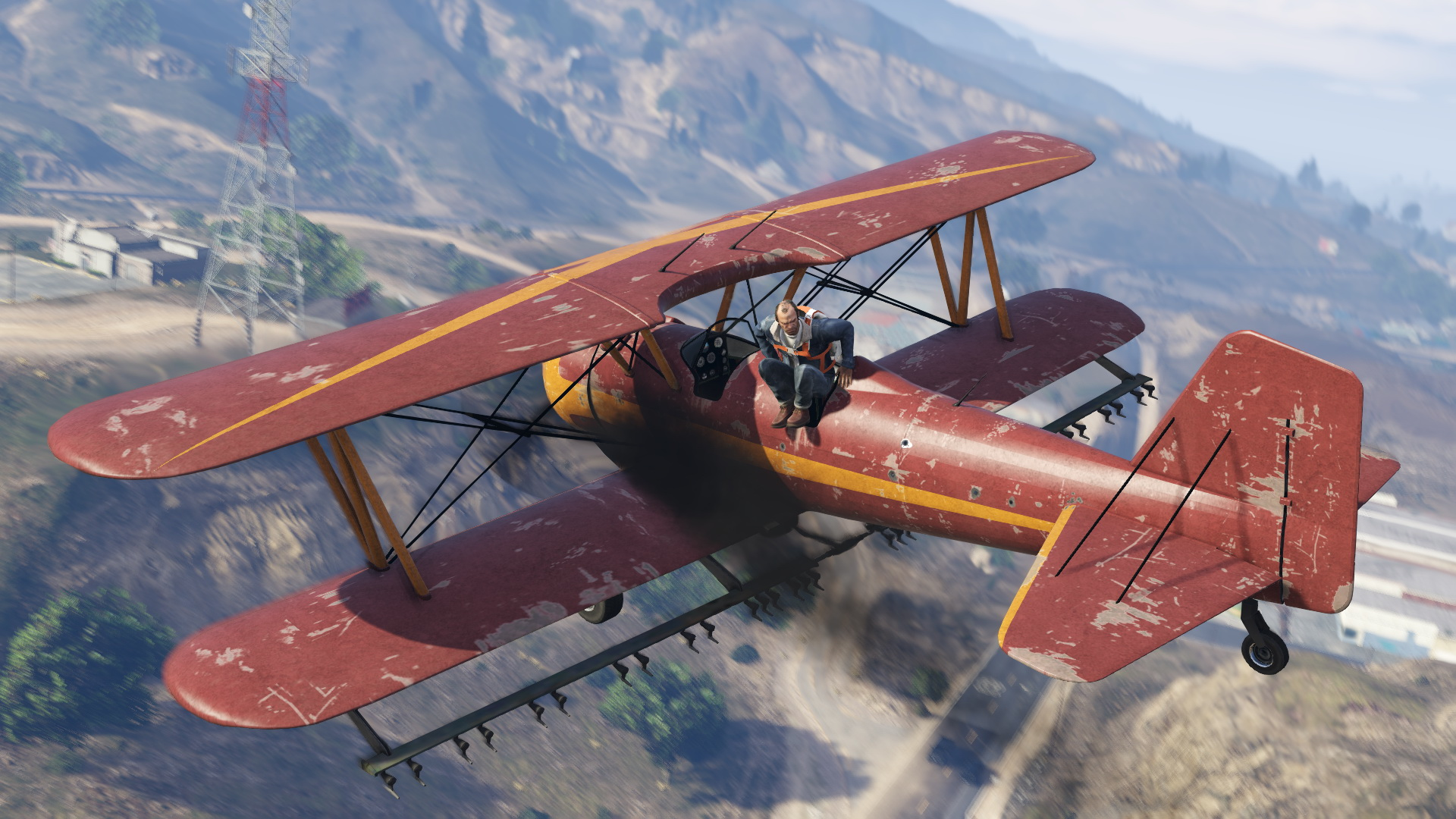 Un biplan vole au-dessus de collines vertes, avec une personne dans le cockpit.