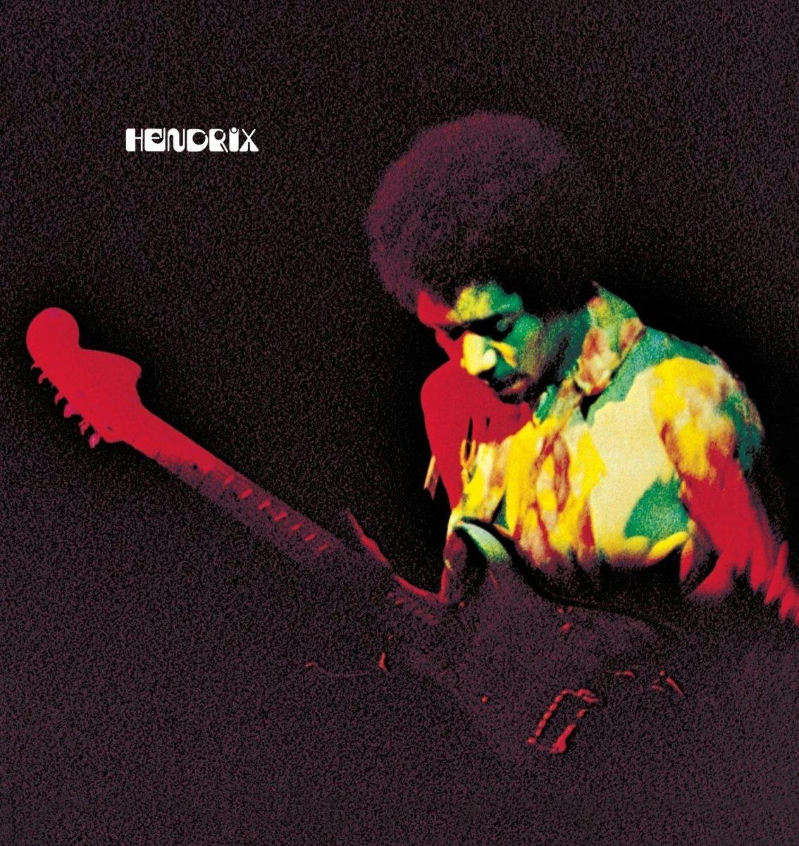 Jimi Hendrix gitározik egy sötét jelenetben, piros és zöld világítással.