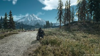 Un hombre montando en moto en un camino de tierra, con un paisaje montañoso al fondo.