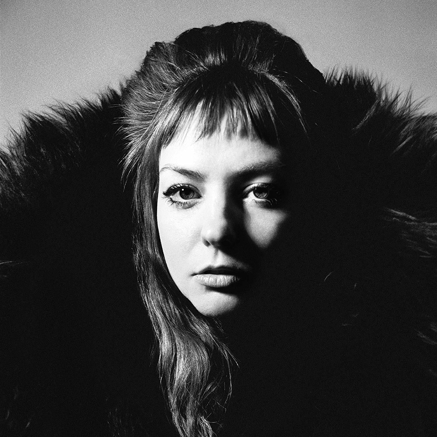 Photo en noir et blanc d'une femme. Elle porte un col en fourrure.