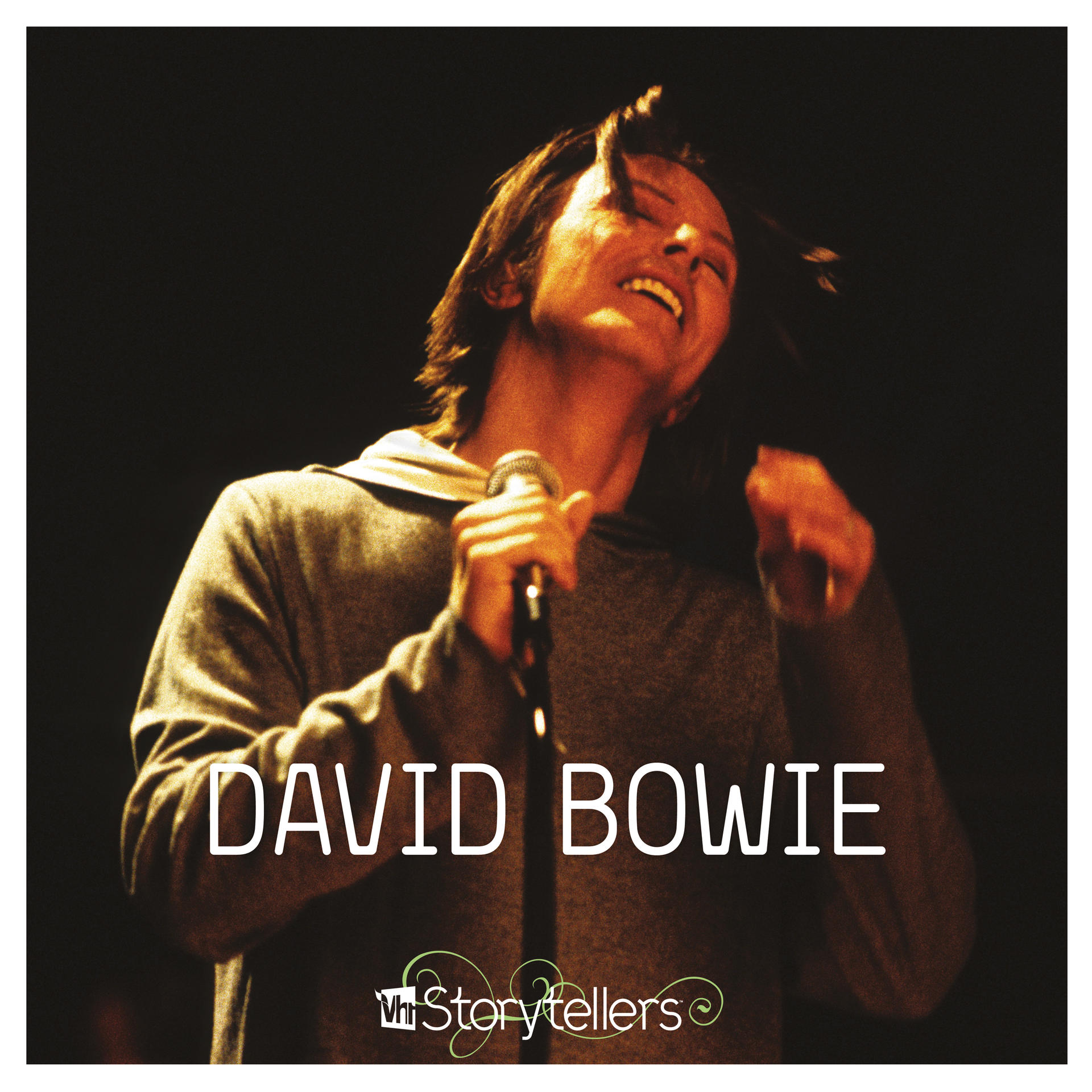 David Bowie énekel. David Bowie mikrofonba énekel. A háttér sötét.