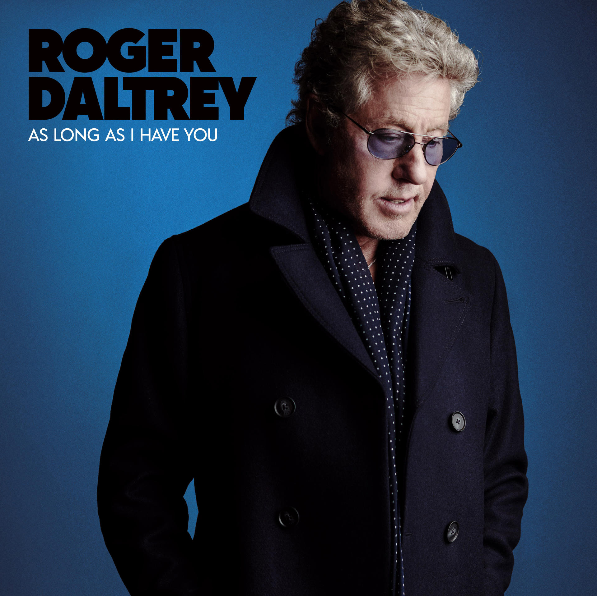 Roger Daltrey in Mantel, Sonnenbrille und Schal, auf blauem Hintergrund.