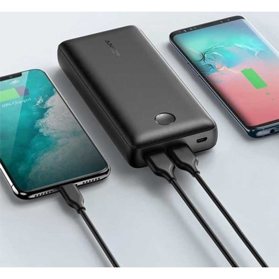 Siyah bir Anker powerbank iki telefonu şarj ediyor. Bir telefon şarj oluyor.
