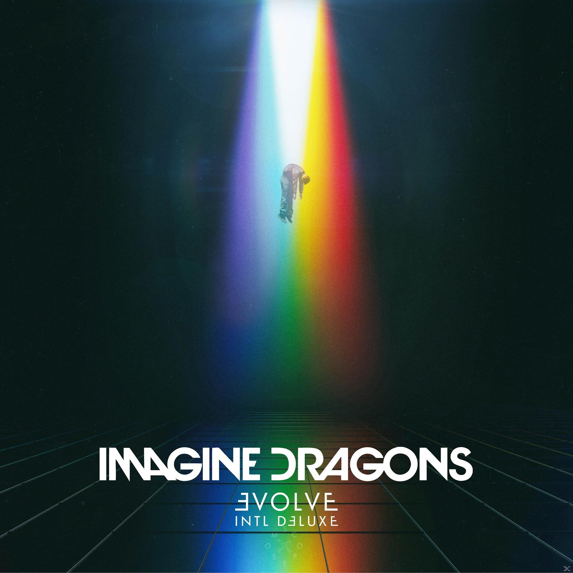 Personne tombant dans un faisceau de lumière arc-en-ciel. Texte Imagine Dragons en blanc en bas.