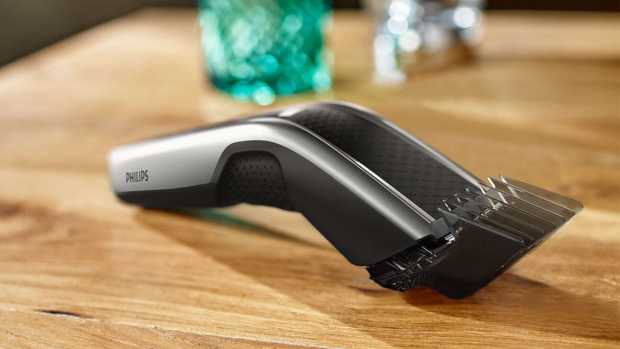 A silver and black Philips hair trimmer on a wooden table.