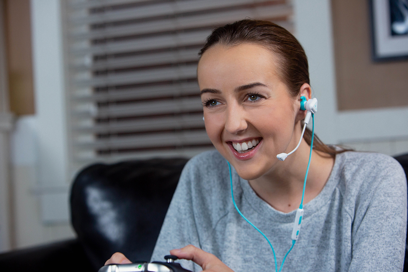 Lachende Frau mit Headset, spielt Videospiel. Controller in den Händen.