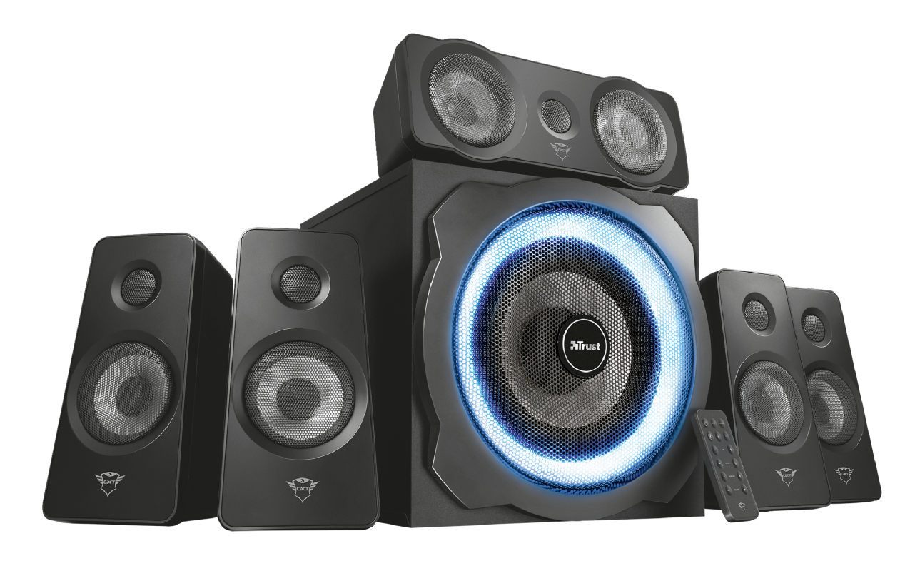 Schwarzes Trust-Lautsprechersystem. Enthält einen Subwoofer mit blauem Lichtring und fünf Satellitenlautsprecher. Eine Fernbedienung liegt vorne.