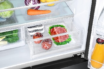 Interior de refrigerador con productos y carne en cajones transparentes.