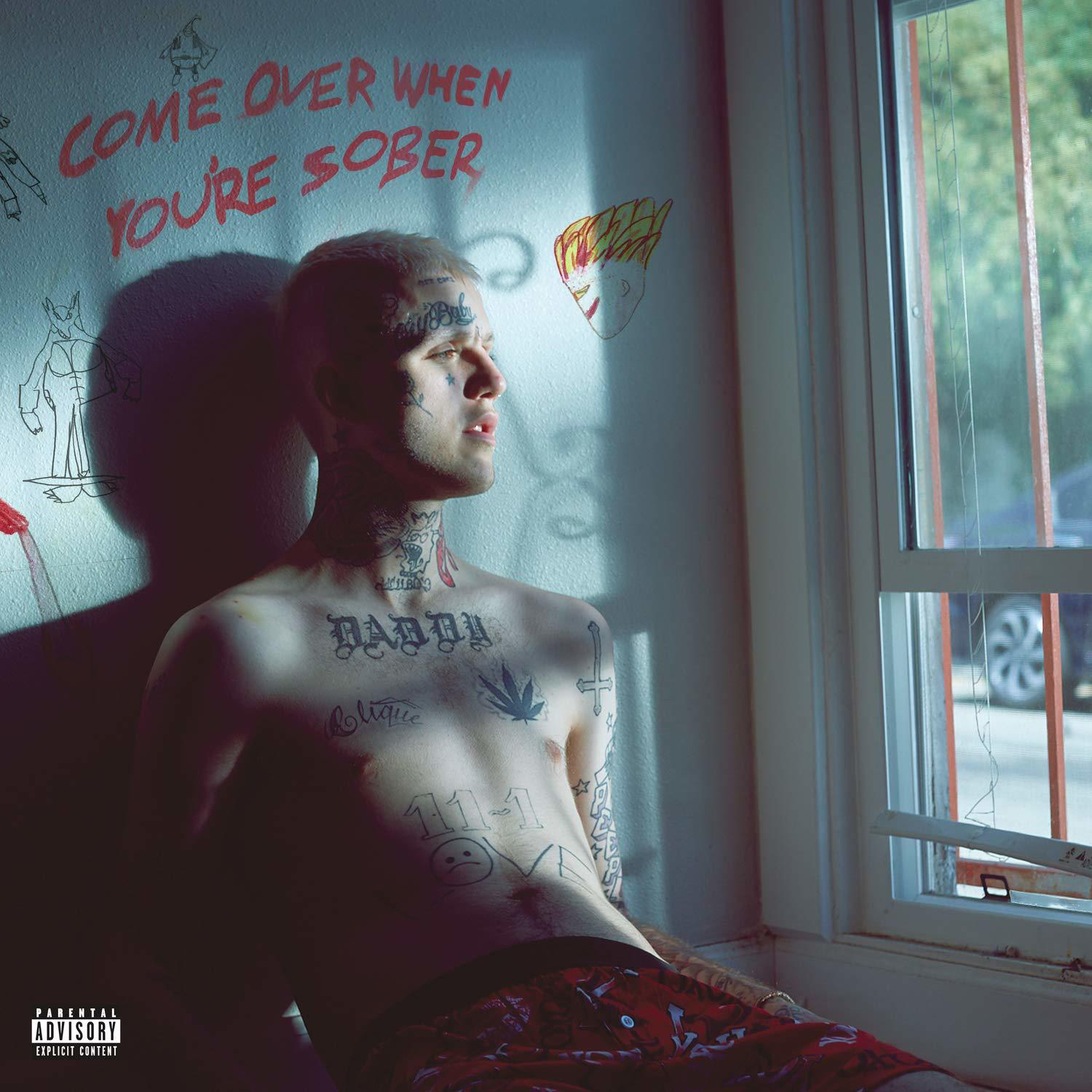 Mann mit Tattoos sitzt in der Nähe eines Fensters mit dem Text 'COME OVER WHEN YOU'RE SOBER' an der Wand.