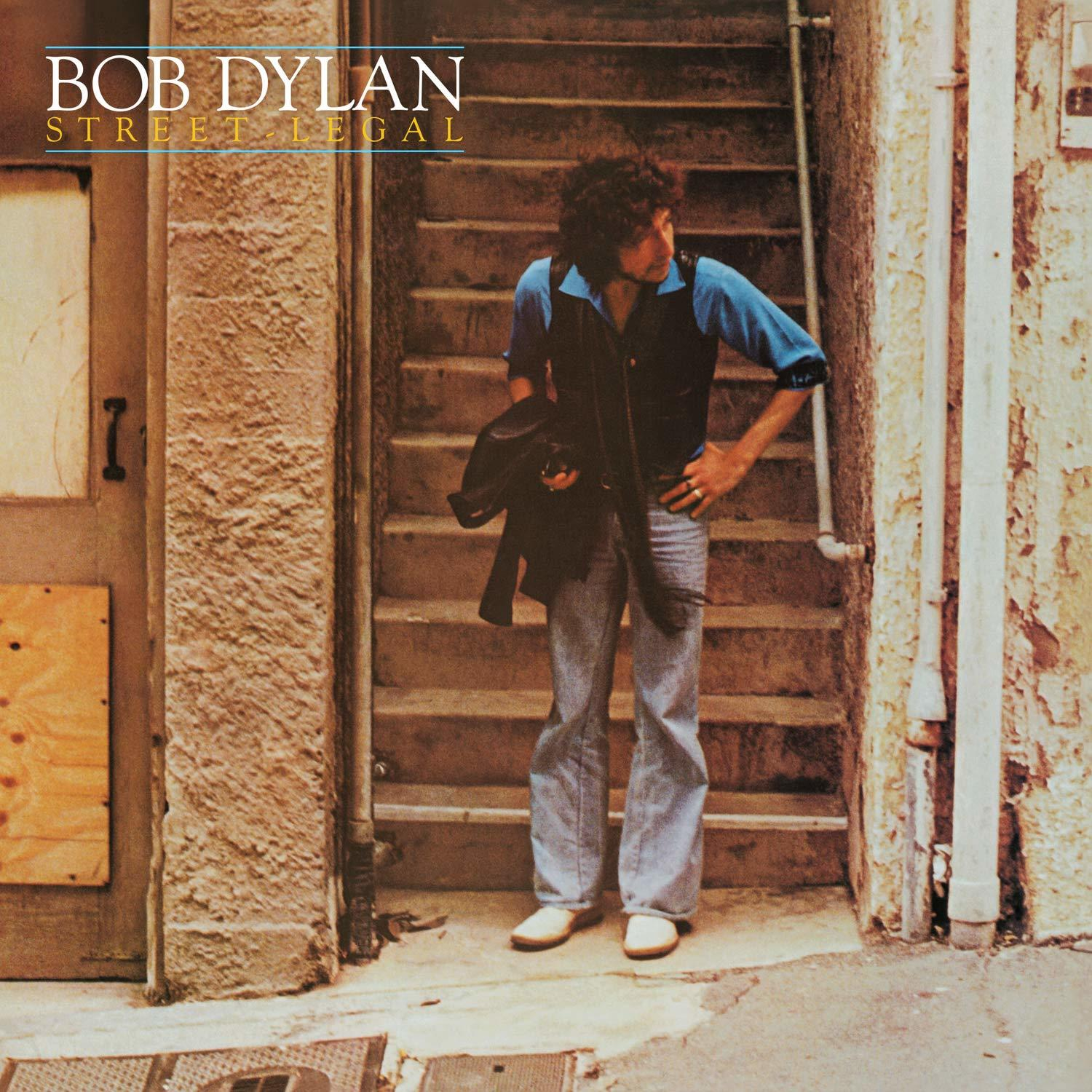 Bob Dylan auf einer Treppe. Er trägt ein blaues Hemd und Jeans. Street Legal Albumcover.