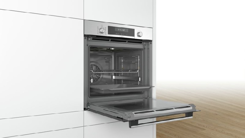 Un horno abierto integrado en un armario blanco. El horno es de acero inoxidable.